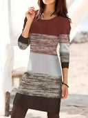 Brown, white, and gray striped long sleeve knit mini dress, front view on a blurred outdoor background.