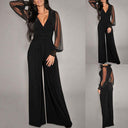 Black jumpsuit with sheer sleeves, V-neck, and studded cuffs, front view.