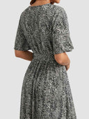 Black and white speckled maxi dress with short sleeves and tie waist, back angled view.