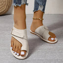 White cream leather flat sandal with buckle cross-strap and open toe-ring detail, angled front view on neutral background.