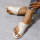 White cream leather flat sandal with padded cross-strap and toe-ring loop, cushioned sole visible, angled view.