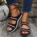 Navy blue mesh platform slide sandals with orange wave trim, worn with distressed jeans on wooden surface, angled front view.