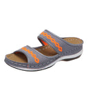 Grey mesh platform slide sandals with orange cross-stitch wave detail and tan cushioned footbed, angled side view.