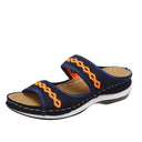 Navy blue mesh platform slide sandal with orange geometric embroidered trim, tan footbed and white rubber sole, angled side view.