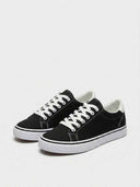 Black low-top canvas sneakers with white lace-up closure and white vulcanised sole, side view.