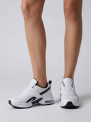 Angled front view of chunky white platform trainers showing breathable mesh upper and black overlay panel detail.