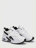 Side profile of white chunky air-sole trainers highlighting the thick ridged rubber outsole and heel pull-tab.