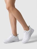 White gel-cushioned trainers worn on feet, showing low-top profile and cushioned midsole, angled view.