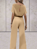 Tan short sleeve jumpsuit with keyhole back, elastic waist, and wide legs, back view.