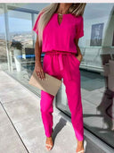 Fuchsia jumpsuit with short sleeves, keyhole neckline, and waist tie, front view.