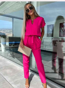 Hot pink jumpsuit with short sleeves, V-neck, and waist tie, front view.