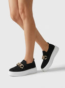 Platform slip-on trainer in black with gold chain detail and stretch knit upper — angled three-quarter view.