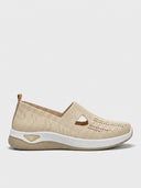 Beige knit slip-on trainers with T-bar cut-out detail and white cushioned soles, angled side view on white background.