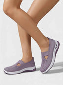 Lilac knit slip-on trainers with white midsoles worn on feet, showing T-bar cut-out vamp detail, angled view.